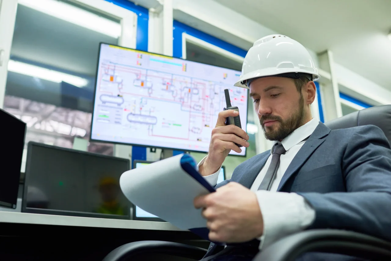 Engineer in office reviewing documents on phone.