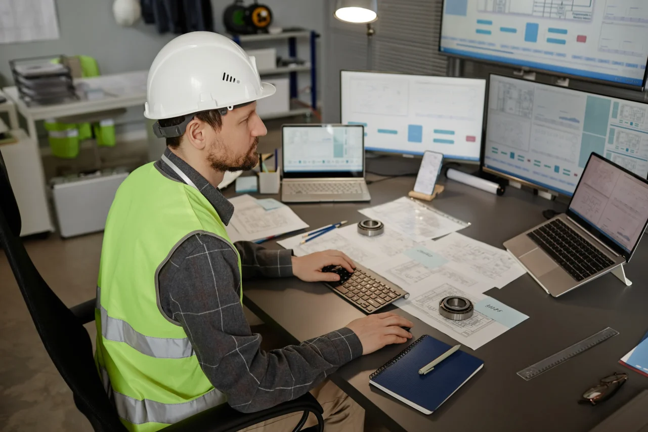 Engineer analyzing digital blueprints at desk setup.