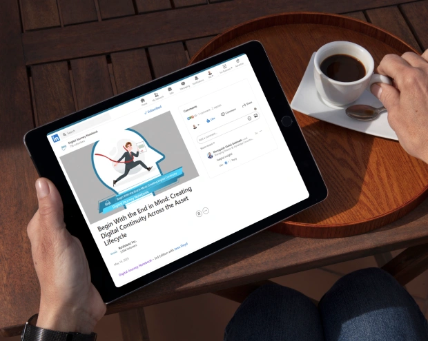 Person reading LinkedIn article on tablet, drinking coffee.