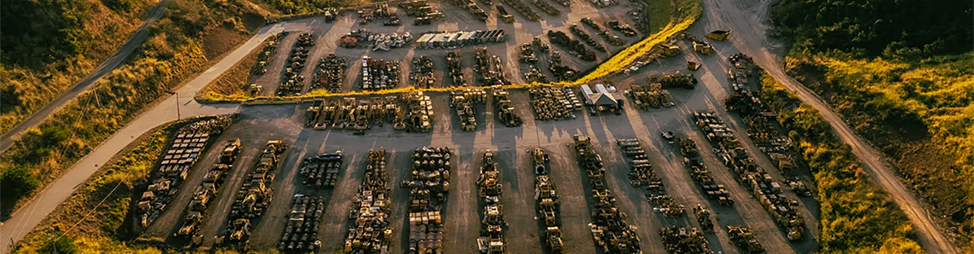 Aerial view of vehicle scrapyard in lush landscape.