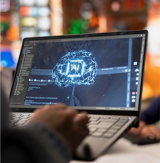Person coding AI on laptop with brain graphic.