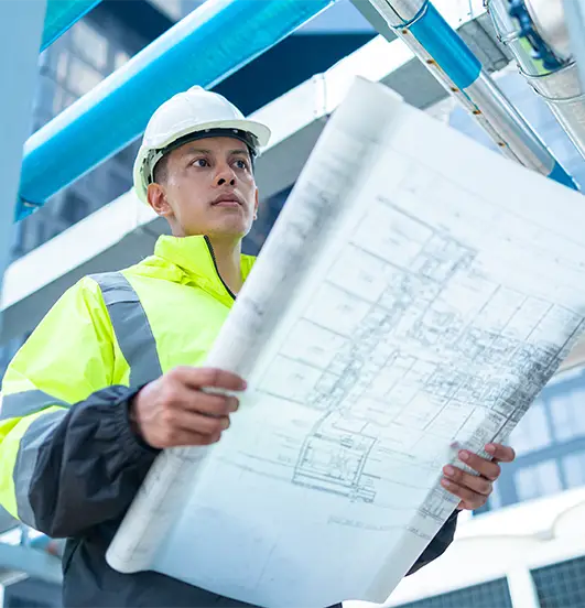 Construction worker reviewing blueprints at industrial site