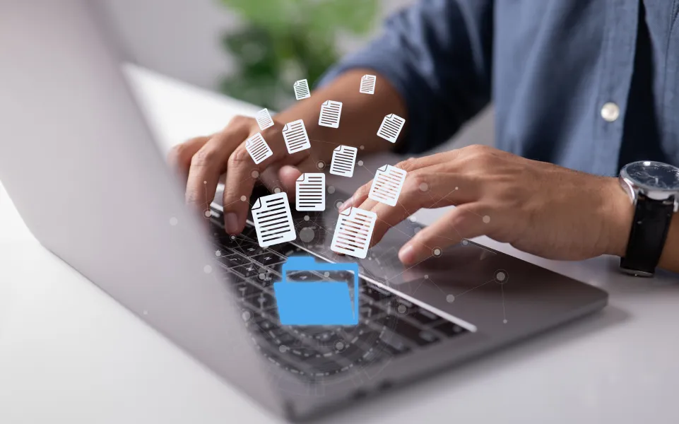 Hands typing on laptop with digital file icons