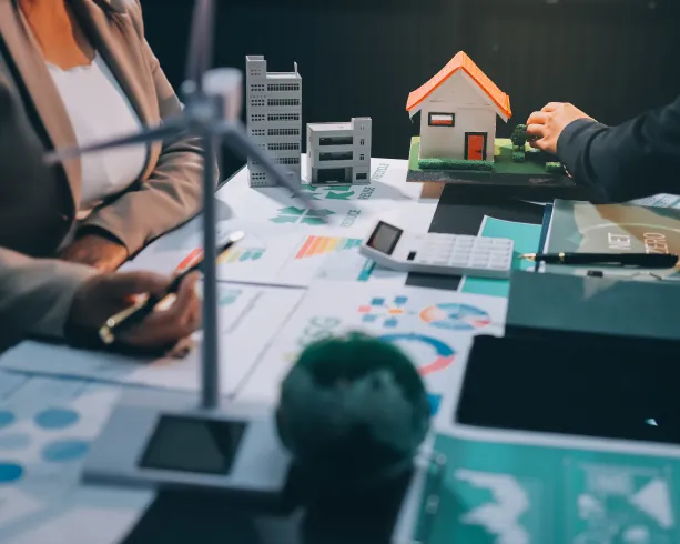 Business meeting with house model and financial charts